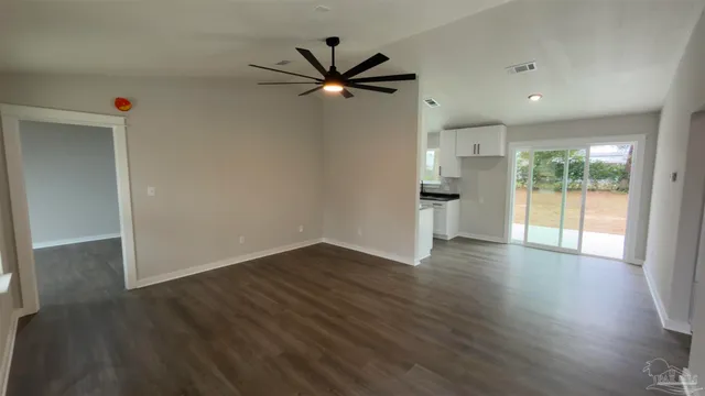 a large kitchen with granite countertop a stove a sink a refrigerator and white cabinets