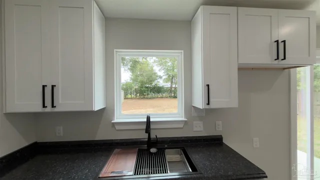 a kitchen with white cabinets and sink
