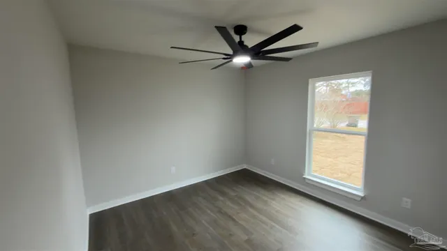 an empty room with wooden floor chandelier fan and windows