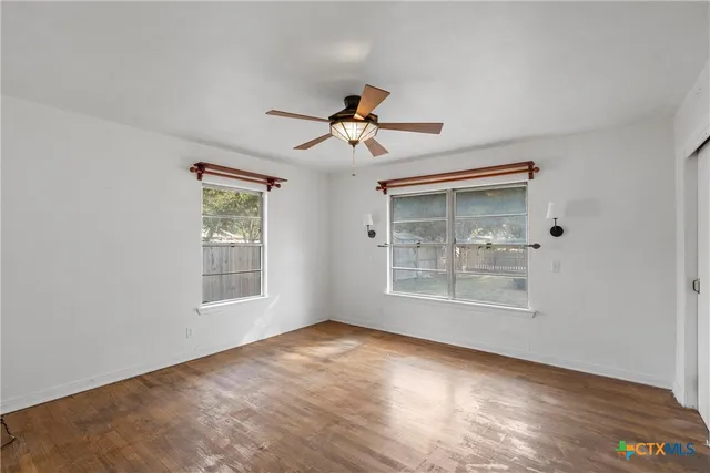 a view of empty room with wooden floor and fan