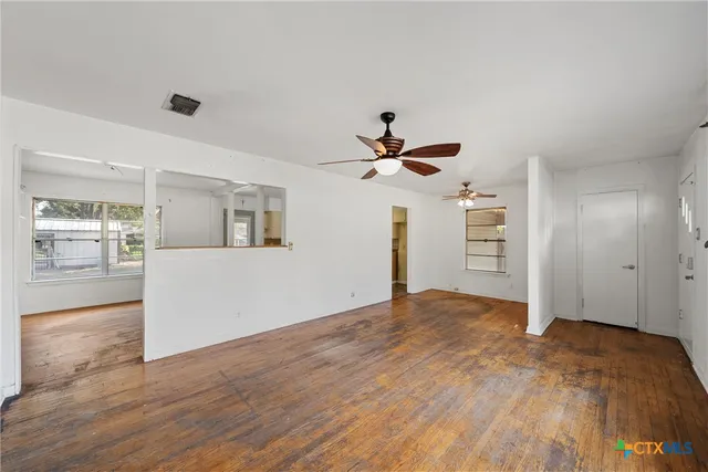a view of empty room with wooden floor and window