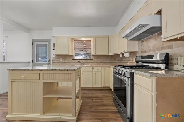 a kitchen with stainless steel appliances granite countertop a stove a sink and a microwave
