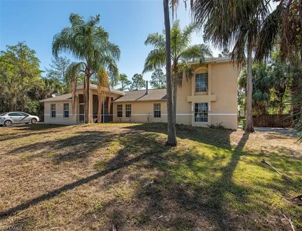 a view of a house with a yard and palm trees