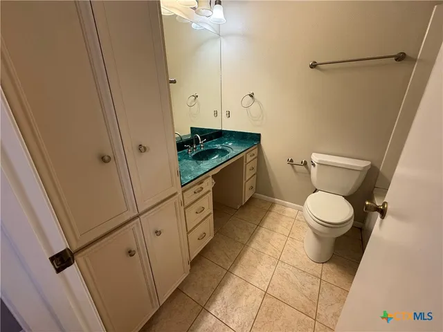 a bathroom with a granite countertop toilet and a sink
