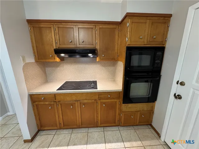 a kitchen with wooden cabinets and a stove top oven