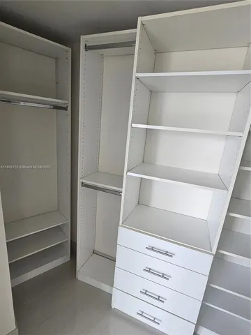 a bedroom with a bed a large window and walk in closet