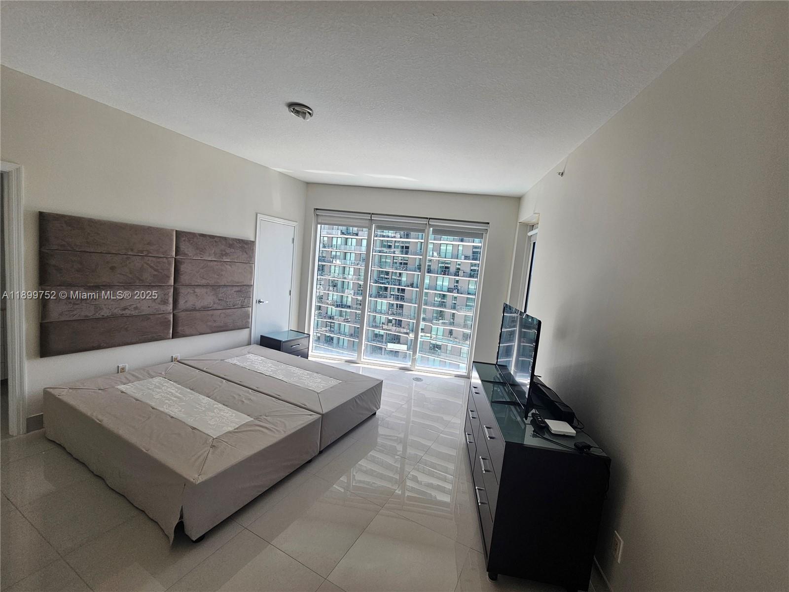 60 Southwest 13th Street, Unit 1900 Miami, FL 33130 - Photo 29 of 95 a spacious bedroom with a bed and a large window