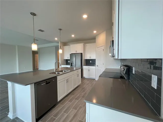 a kitchen with granite countertop a sink a counter top space stainless steel appliances and cabinets