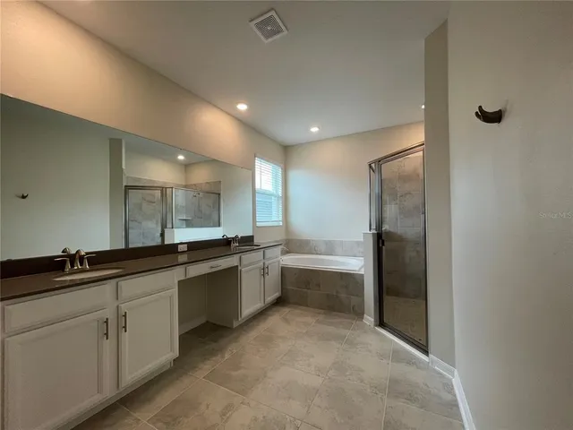 a large bathroom with a double vanity sink a large mirror and a bathtub