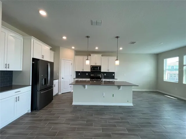 a large kitchen with a center island stainless steel appliances and cabinets