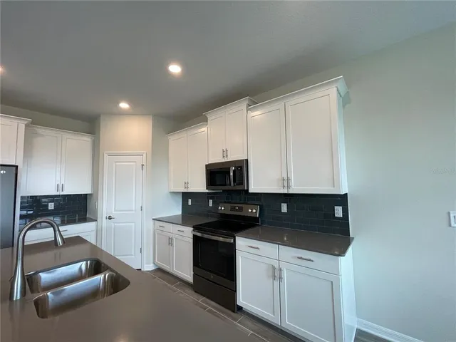 a kitchen with granite countertop white cabinets and black appliances