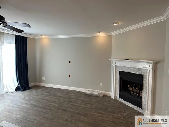 a view of an empty room with wooden floor fireplace and a window