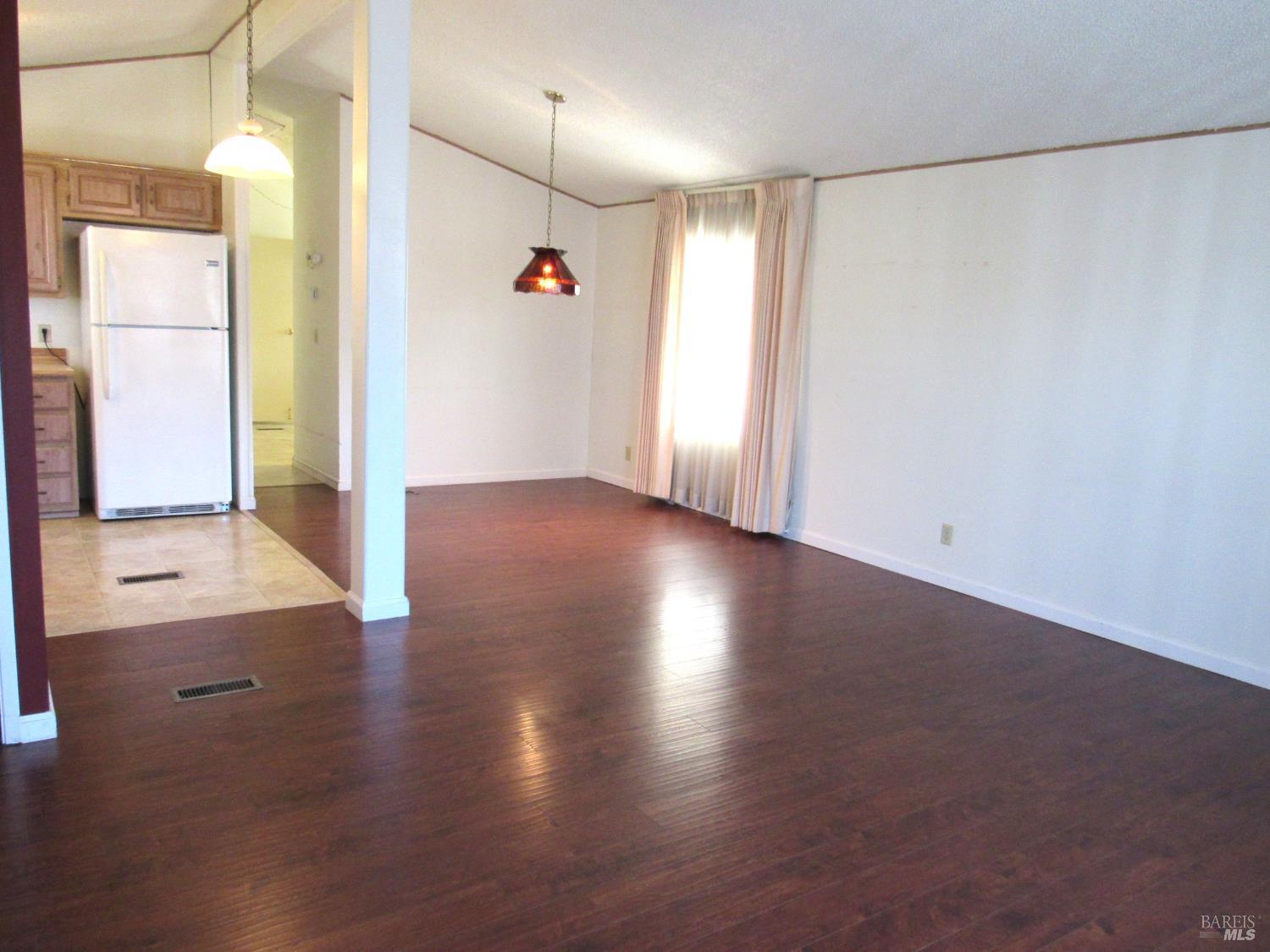 31 Ramon Street Sonoma, CA 95476 - Photo 9 of 24 an empty room with wooden floor and windows with curtains