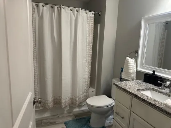 a bathroom with a granite countertop sink and a toilet