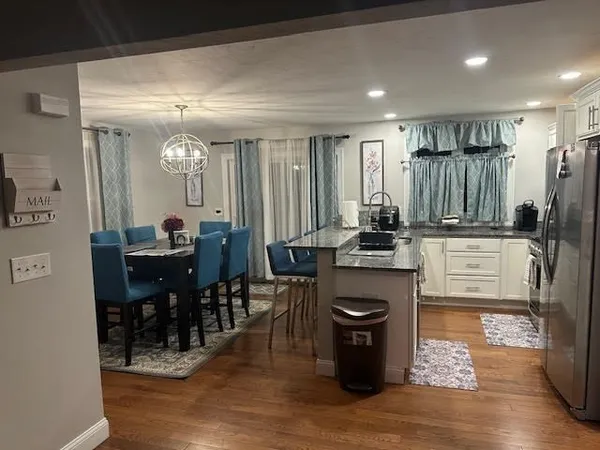 a kitchen with stainless steel appliances granite countertop a sink a stove a refrigerator cabinets and chairs