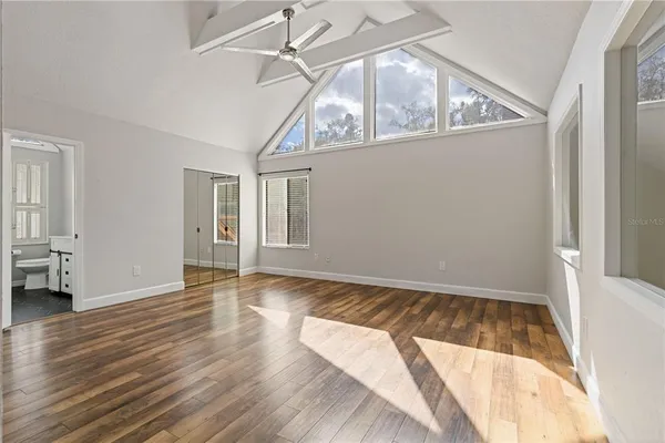a view of an empty room with wooden floor and a window