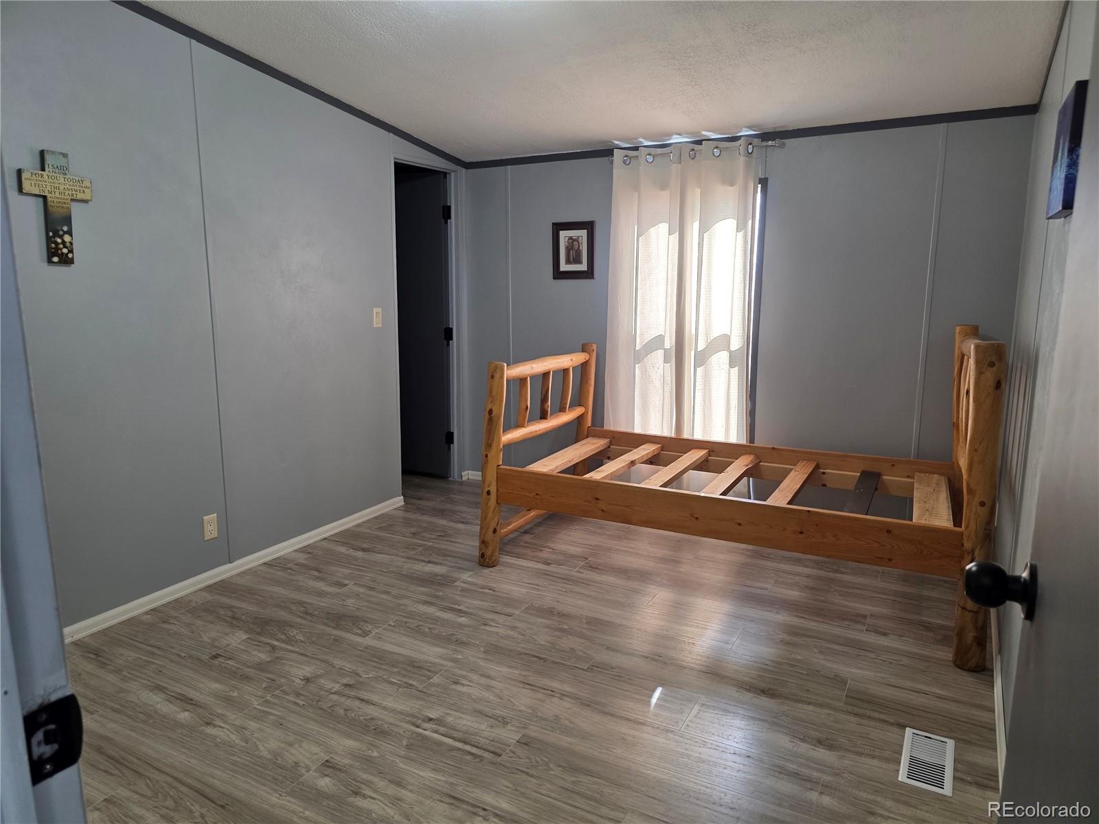 7881 Foothill Boulevard Alamosa, CO 81101 - Photo 13 of 25 an empty room with wooden floor and windows