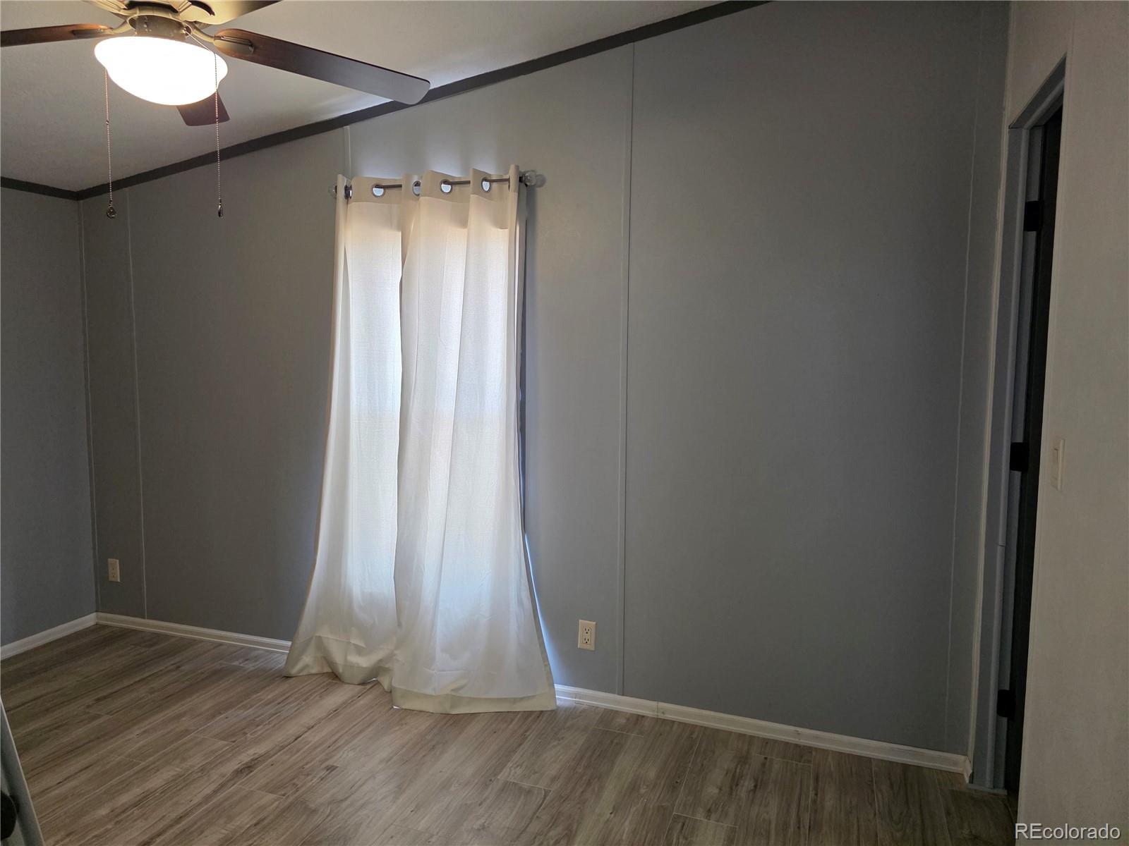 7881 Foothill Boulevard Alamosa, CO 81101 - Photo 14 of 25 an empty room with wooden floor and windows