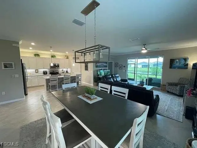 a kitchen with stainless steel appliances kitchen island granite countertop a dining table chairs refrigerator and stove
