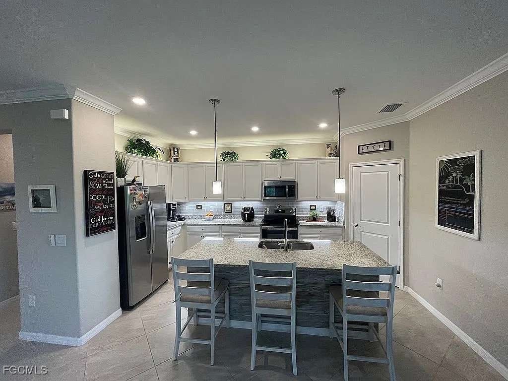 2190 Clementine Street Naples, FL 34120 - Photo 9 of 16 a kitchen with stainless steel appliances kitchen island granite countertop a dining table chairs refrigerator and stove