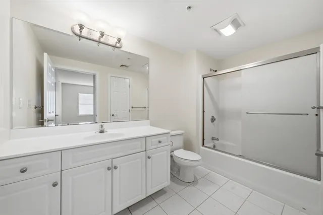 a spacious bathroom with a double vanity sink a mirror and a toilet