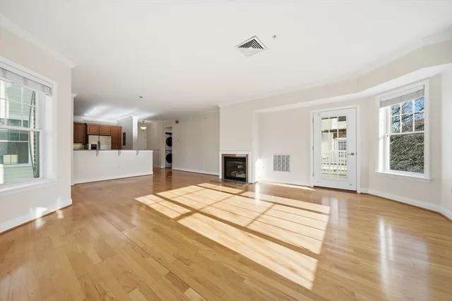 a view of an empty room with window and wooden floor