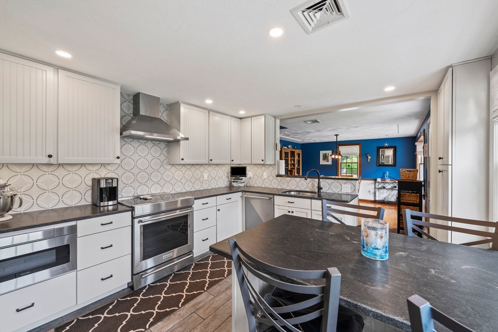 7 Signal Hill Road Marshfield, MA 02050 - Photo 5 of 42 a kitchen with stainless steel appliances granite countertop a stove top oven a sink a dining table and chairs