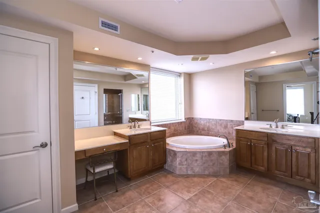 a bathroom with a granite countertop bathtub sink vanity mirror and toilet