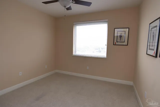 an empty room with a chandelier fan and windows