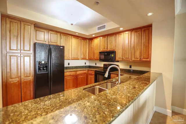 a kitchen with granite countertop a refrigerator and a sink