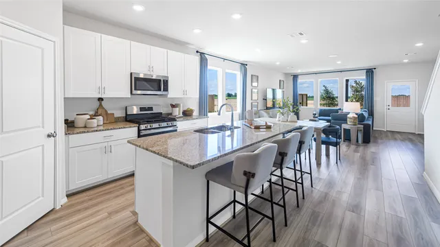 a kitchen with sink a microwave oven a stove and white cabinets with wooden floor