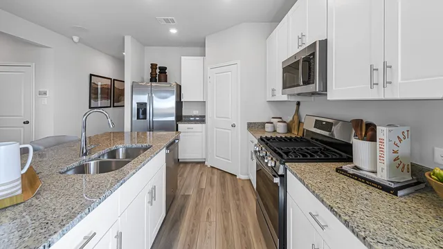 a kitchen with granite countertop kitchen island stainless steel appliances a sink stove top oven and microwave