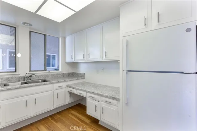 a kitchen with a sink dishwasher a refrigerator and white cabinets