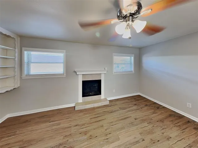a view of an empty room with window and wooden floor