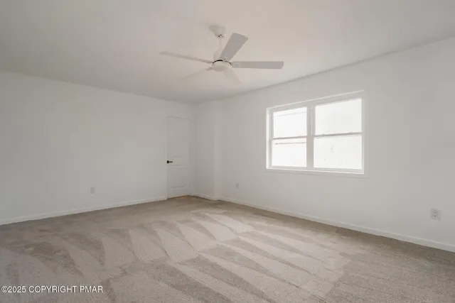 an empty room with a window and ceiling fan