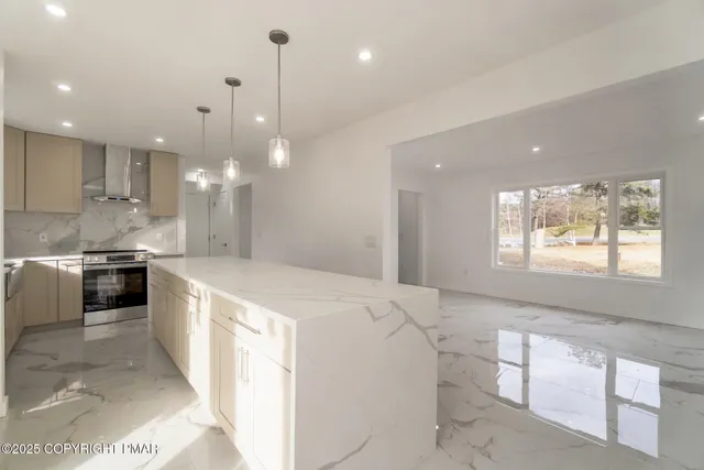 a large kitchen with kitchen island a large counter top a stove a sink and a refrigerator