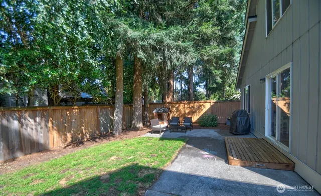 a view of backyard with wooden fence and a large tree