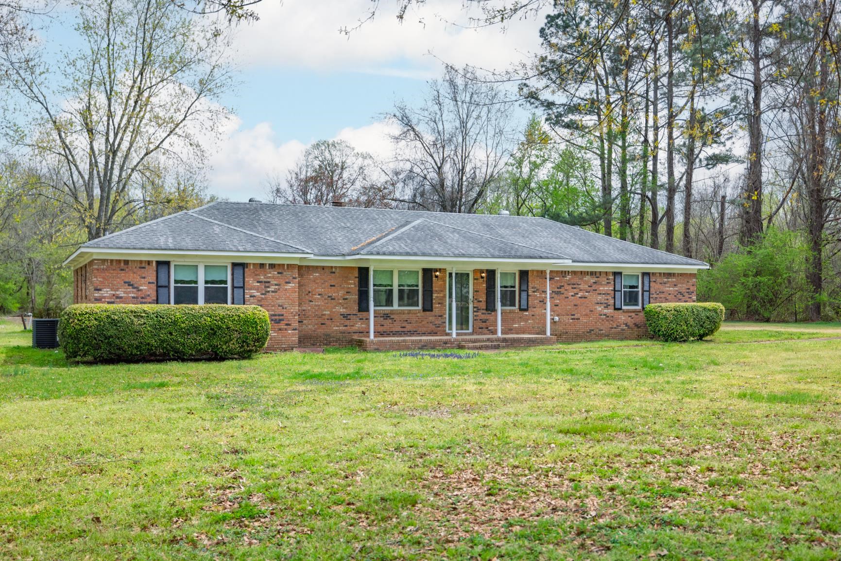Ranch-style house featuring brick siding, a front lawn, and a shingled roof