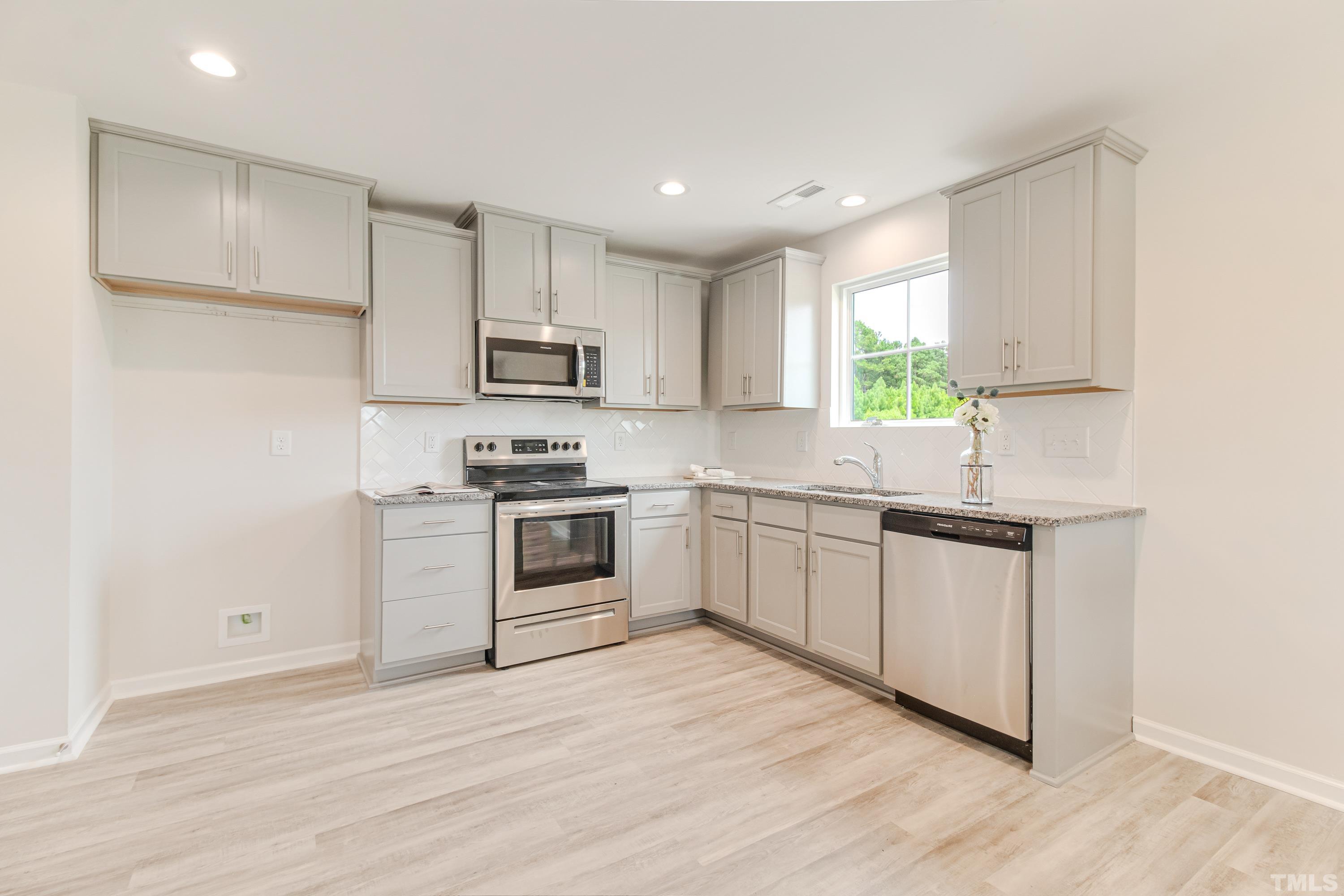 385 Dasu Drive Clayton, NC 27520 - Photo 14 of 33 a kitchen with granite countertop white cabinets and white appliances