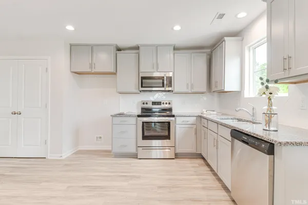 a kitchen with granite countertop a stove top oven sink and cabinets