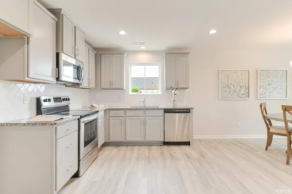 a kitchen with granite countertop white cabinets and white appliances