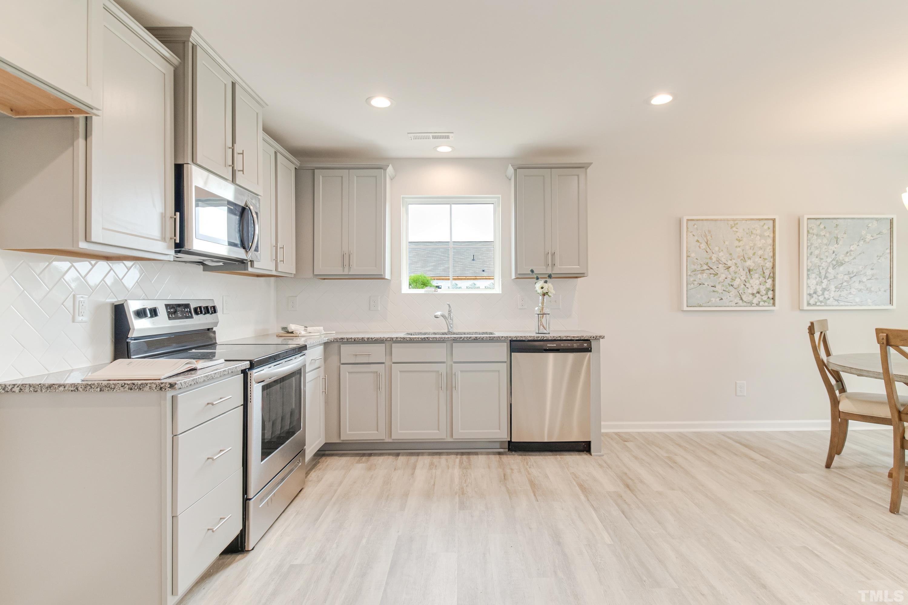 385 Dasu Drive Clayton, NC 27520 - Photo 16 of 33 a kitchen with granite countertop white cabinets and white appliances