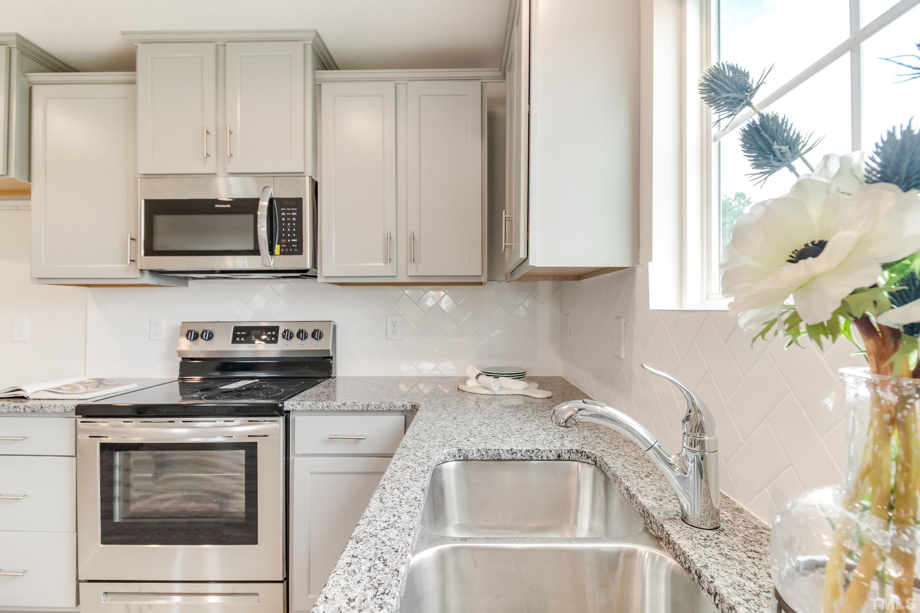 385 Dasu Drive Clayton, NC 27520 - Photo 17 of 33 a kitchen with granite countertop a stove microwave and sink