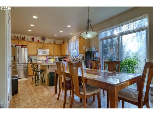 a kitchen with stainless steel appliances kitchen island granite countertop a table chairs and white cabinets