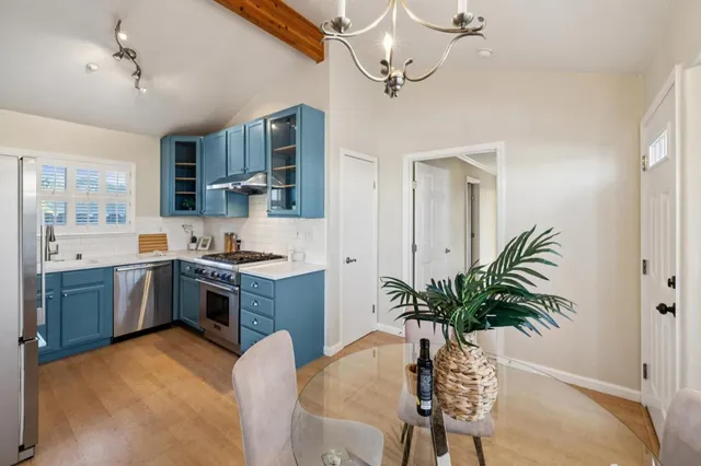 a kitchen with a chandelier a sink stainless steel appliances and cabinets