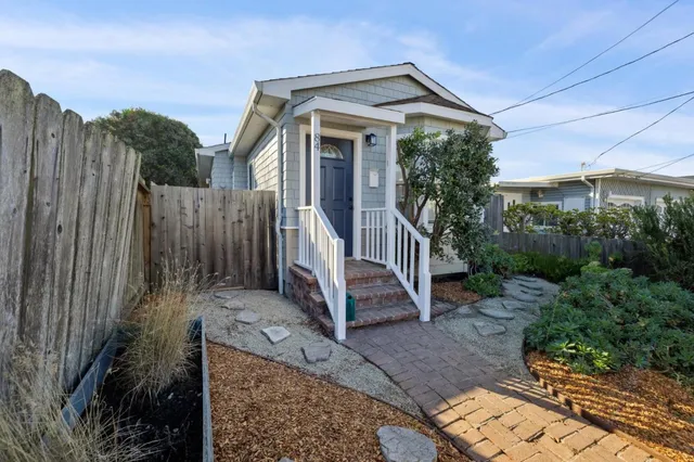 a view of a house with wooden fence next to a yard