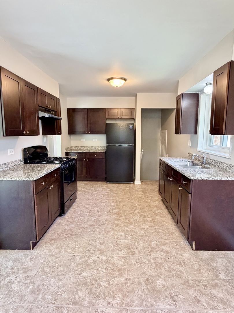 1820 169th Street Hazel Crest, IL 60429 - Photo 10 of 23 a large kitchen with kitchen island granite countertop a refrigerator and a stove top oven