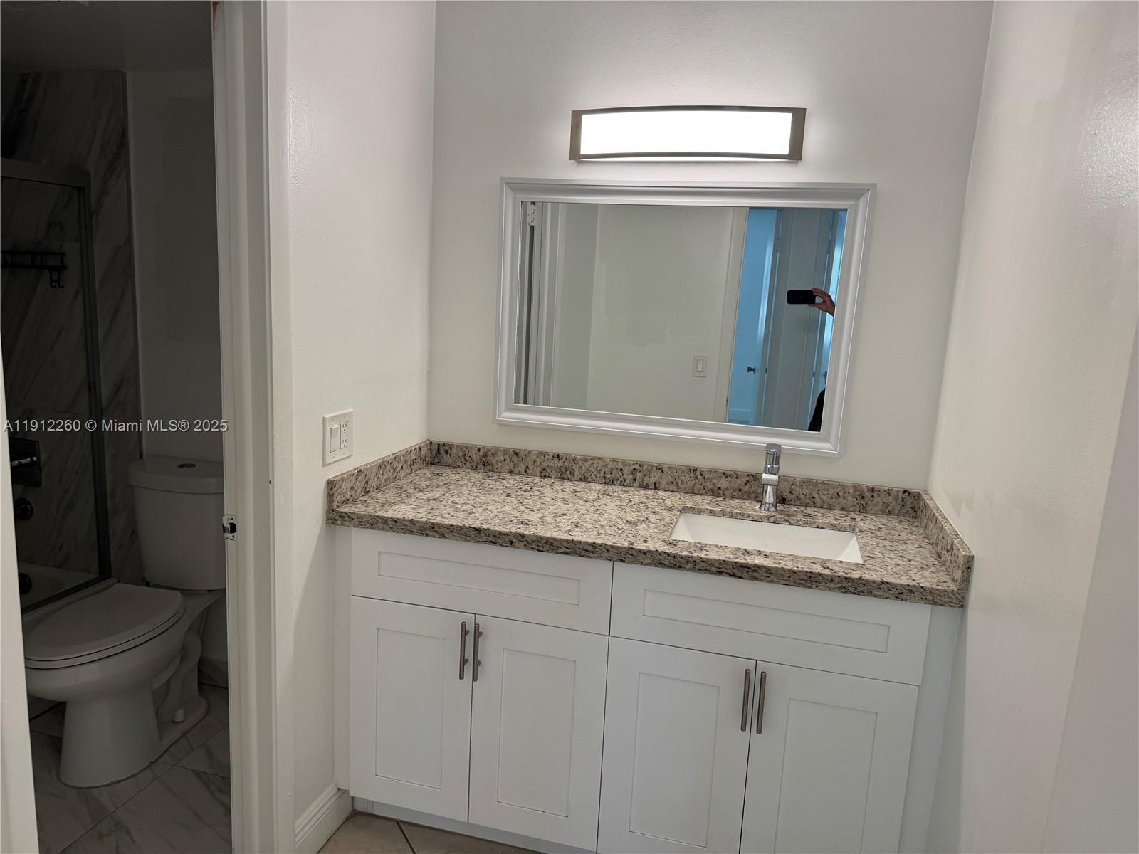 15630 Southwest 80th Street, Unit I209 Miami, FL 33193 - Photo 11 of 19 a bathroom with a granite countertop sink vanity mirror and toilet