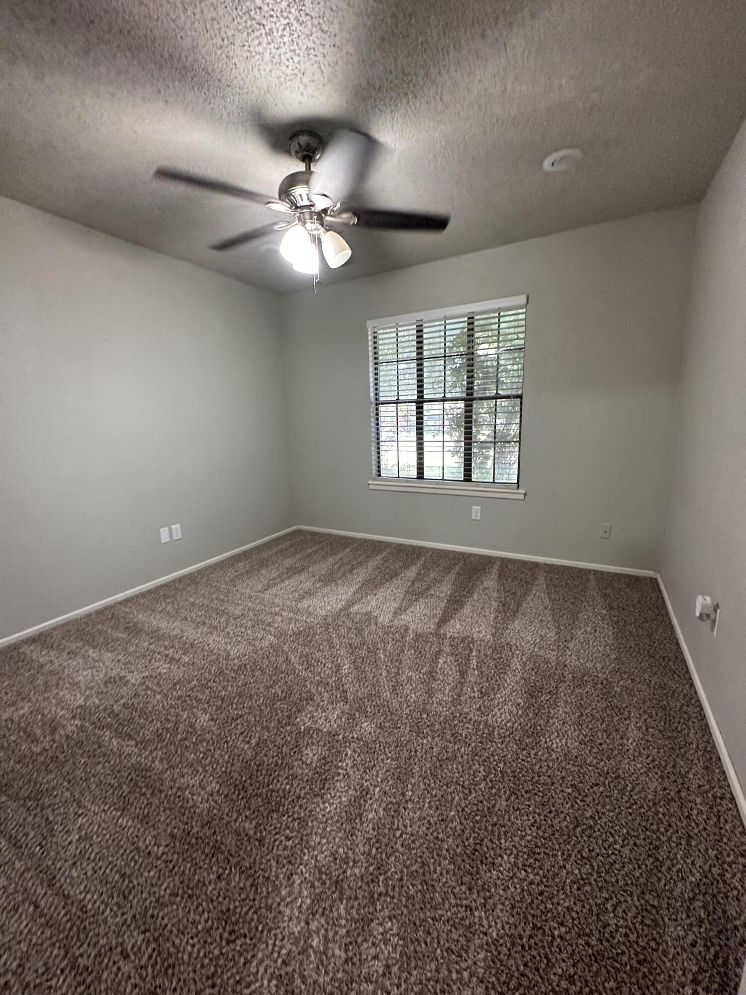 4804 71st Street Lubbock, TX 79424 - Photo 11 of 14 an empty room with windows and fan chandelier
