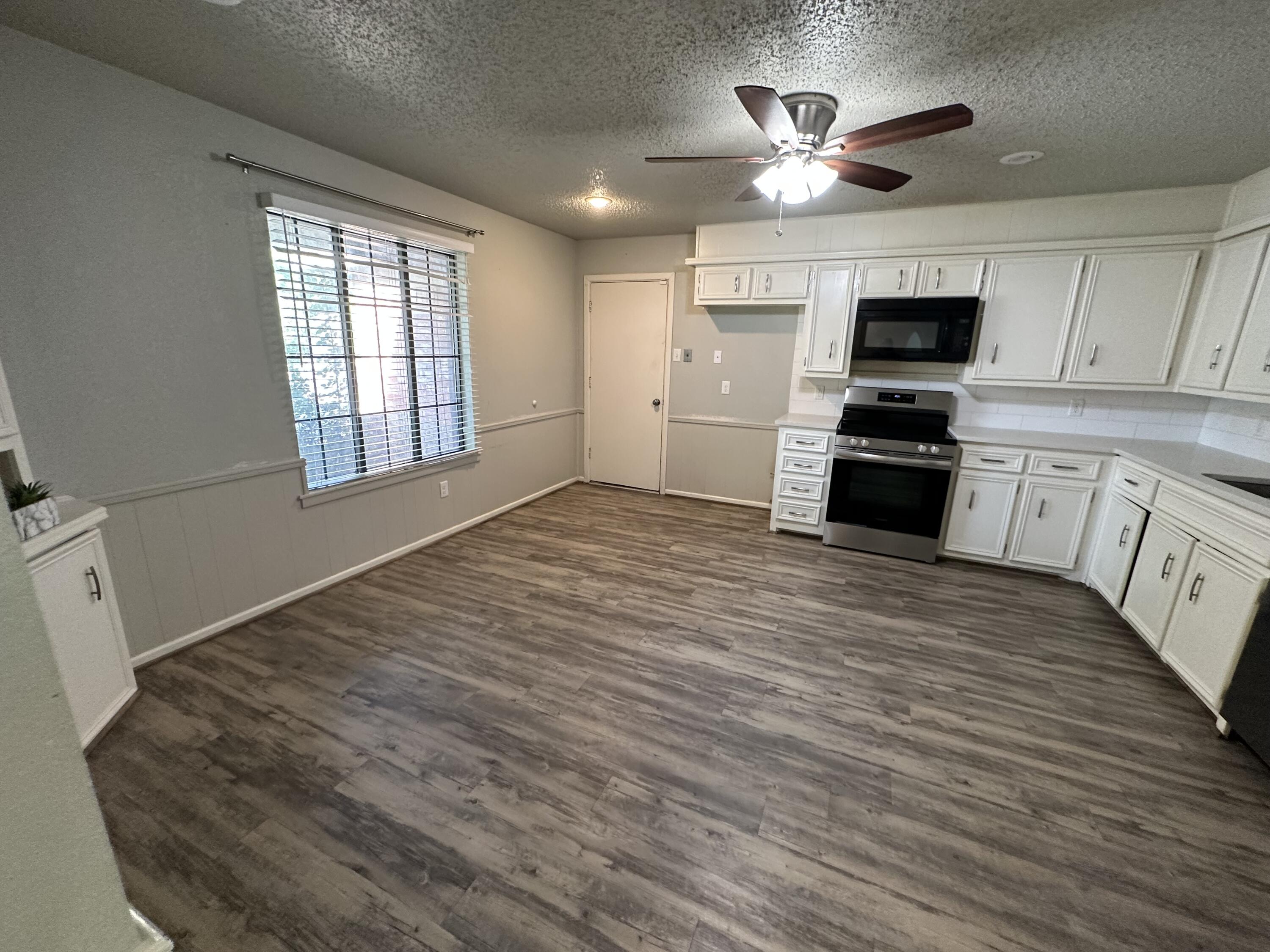 4804 71st Street Lubbock, TX 79424 - Photo 4 of 14 a kitchen with stainless steel appliances kitchen island granite countertop a stove a sink and a refrigerator
